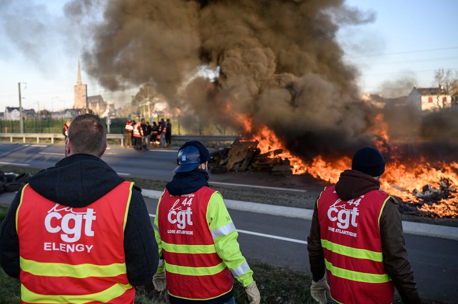Des dizaines de syndicalistes bloquent une route avec un feu devant la raffinerie Total Energies lors d'une action appelée par la Confédération générale du travail (CGT) contre une réforme des retraites profondément impopulaire à Donges, dans l'ouest de la France, le 8 février 2023.