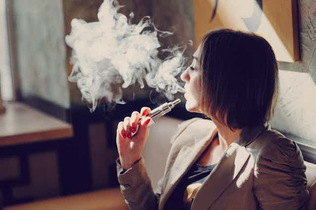 Mujer echando el vapor de un cigarrillo electrónico.