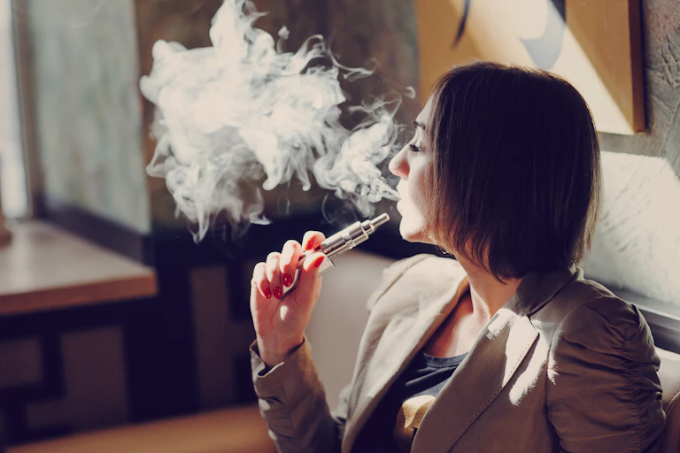 Mujer echando el vapor de un cigarrillo electrónico.