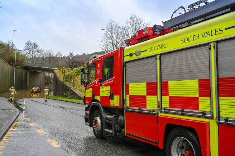 The fire service attending to a vehicle stuck in floodwater.