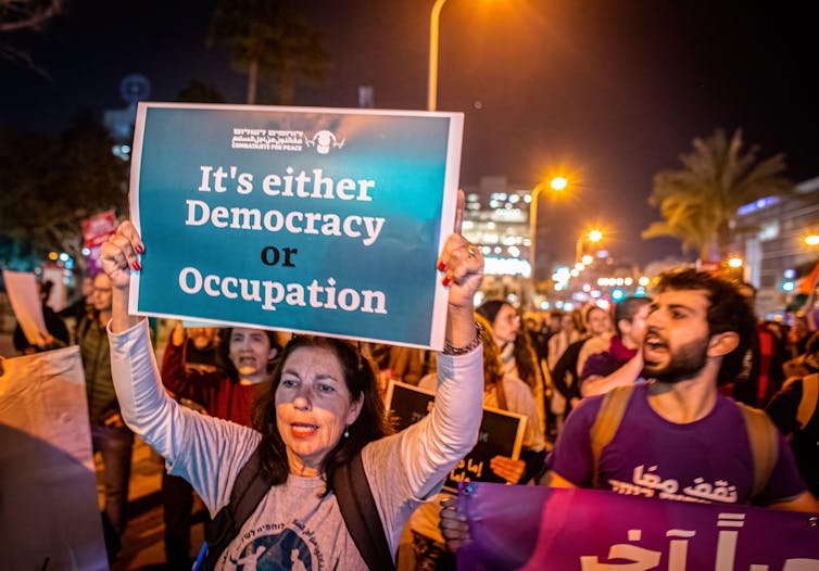 Israelis hold up placards condemning their government's occupation of Palestinian areas.