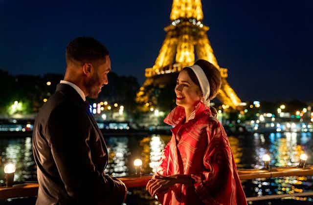 Una mujer y un hombre hablan con la Torre Eiffel de fondo.