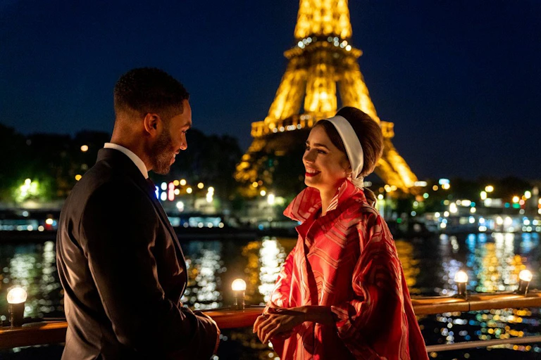 Una mujer y un hombre hablan con la Torre Eiffel de fondo.