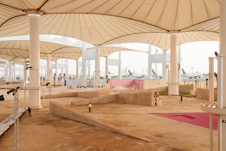 A vast interior space with columns holding up canopies and aeroplanes in the distance.