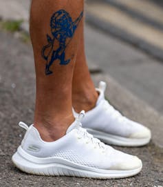 A lion tattoo on a man's calf.