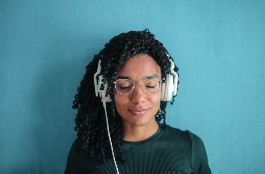 Woman wearing headphones against blue background.