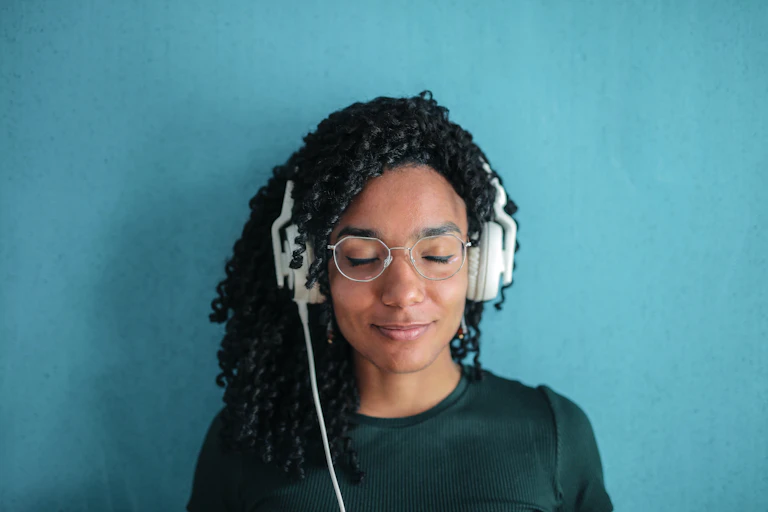 Woman wearing headphones against blue background.