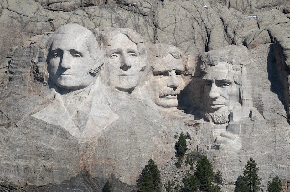 The massive sculpted heads of four men adorn the side of a mountain.