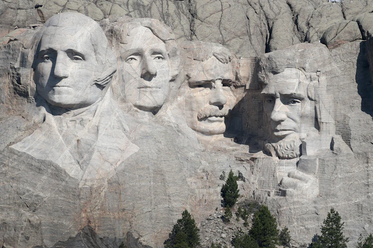 The massive sculpted heads of four men adorn the side of a mountain.