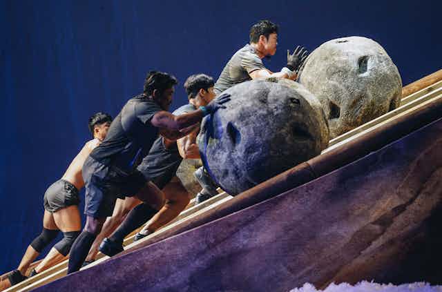 Contestants pushing boulders up a slope