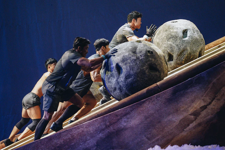 Contestants pushing boulders up a slope