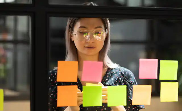 A woman puts sticky notes on a window