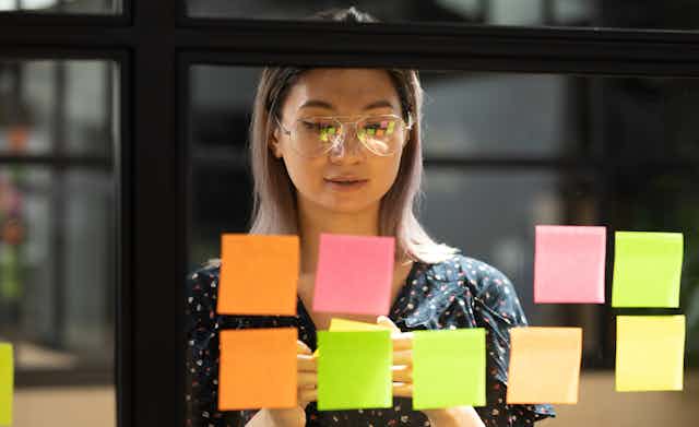 A woman puts sticky notes on a window
