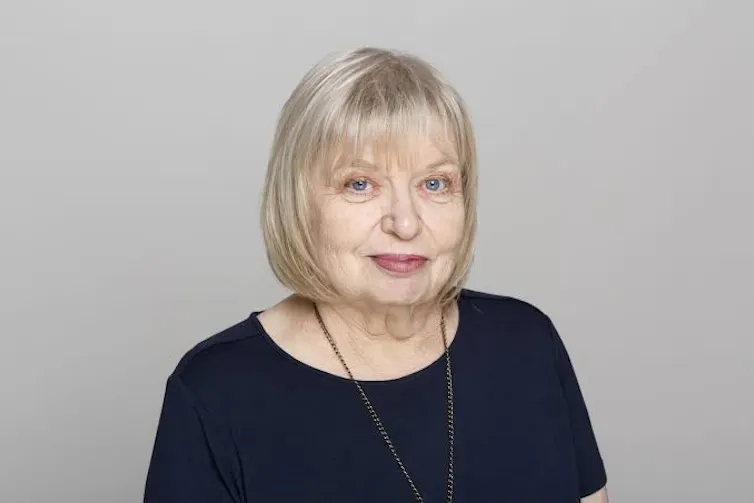 A white woman with a silver-blonde bob and a black T-shirt