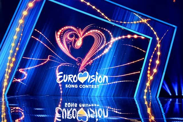 A stage with a lit background saying "Eurovision". The V is styled as a heart containing the Ukrainian flag.