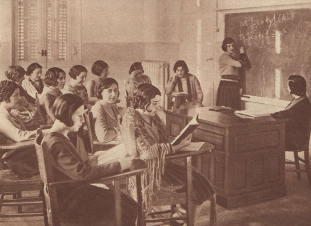 Foto antigua de mujeres sentadas en pupitres en una clase. 