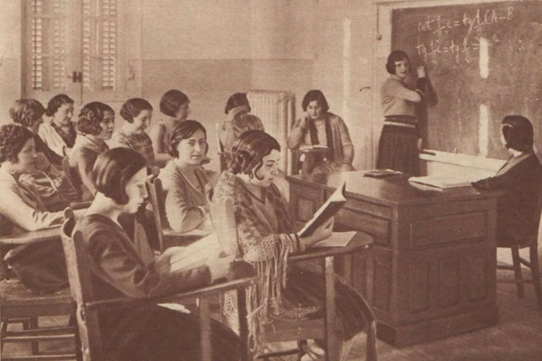 Foto antigua de mujeres sentadas en pupitres en una clase.