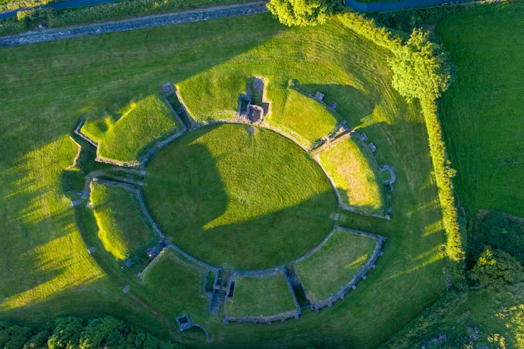 An aerial view of the remains of the Caerleon amphitheatre now covered in grass.