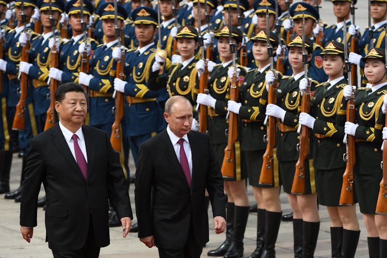 Putin and Jinping walk in front of a formal display of military personnel