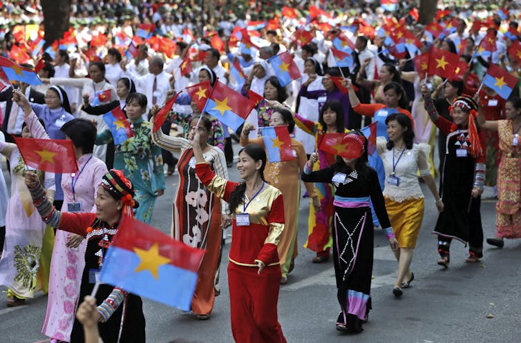 Women take part in a parade waving flags.