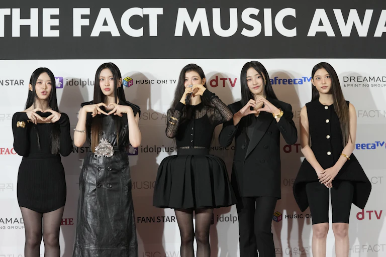 Five young women wearing black outfits pose for a photo.