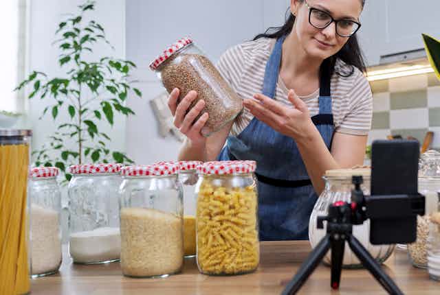 Woman holds jar of food in front of a smartphone camera.