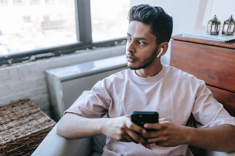 Young man browses his phone, with serious expression