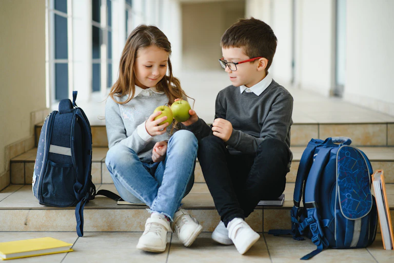 Un niño y una niña con una manzana cada uno.