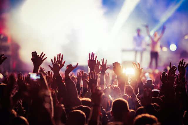 Multitud levantando las manos en un concierto.