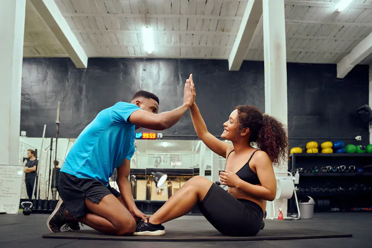 A young couple high five in the gym.