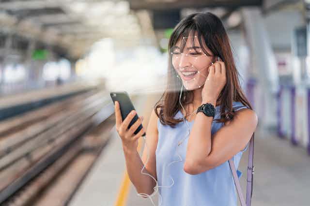 Mujer asiática usa el reconocimiento facial a través de un smartphone.