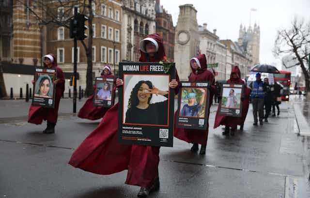 Women wearing headcoverings and carrying photographs of women killed by the Iranian authorities march in London.