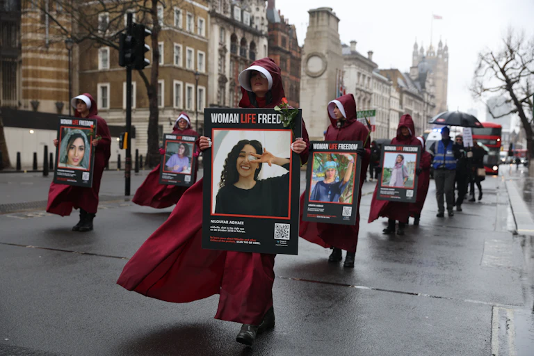 Women wearing headcoverings and carrying photographs of women killed by the Iranian authorities march in London.