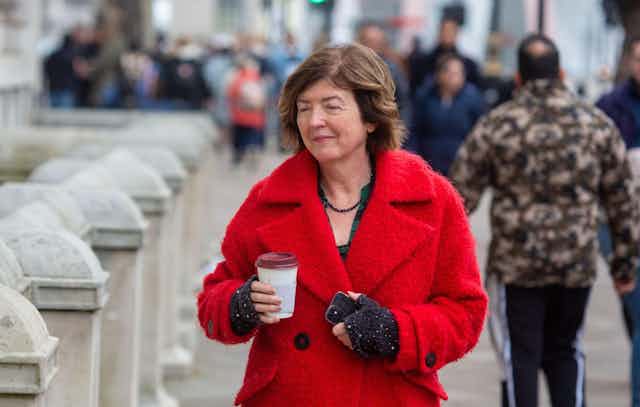 Sue Gray walking down the street with a coffee.