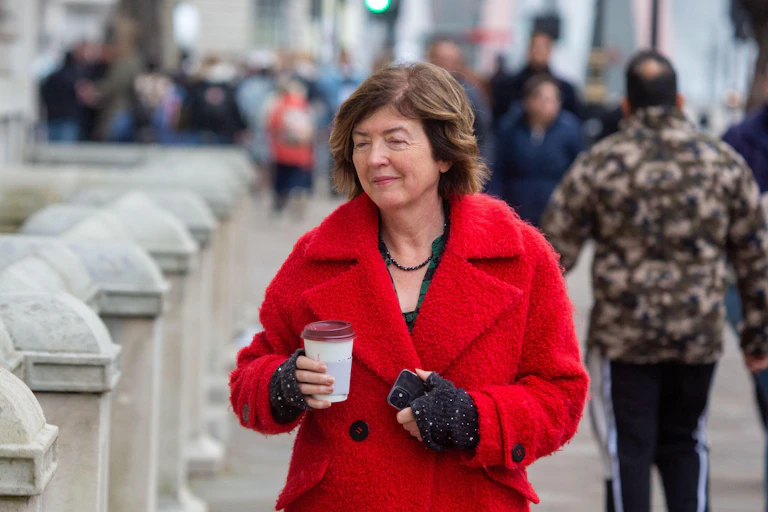 Sue Gray walking down the street with a coffee.