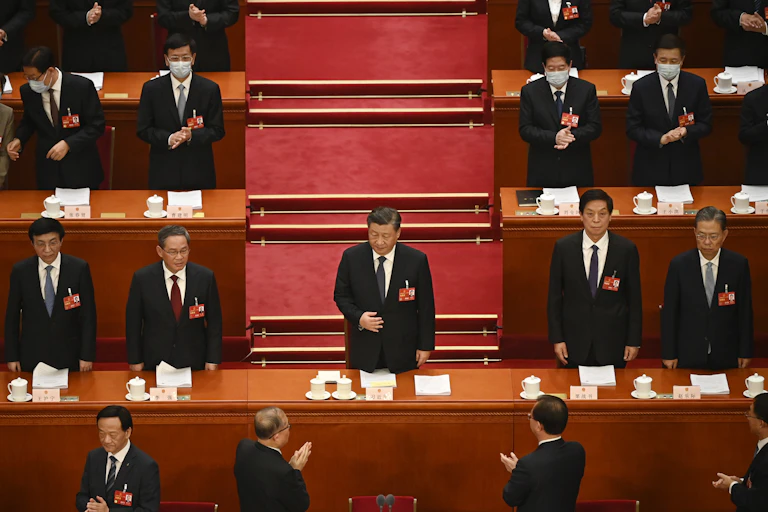 Xi Jinping debout entouré d'hommes qui l'applaudissent