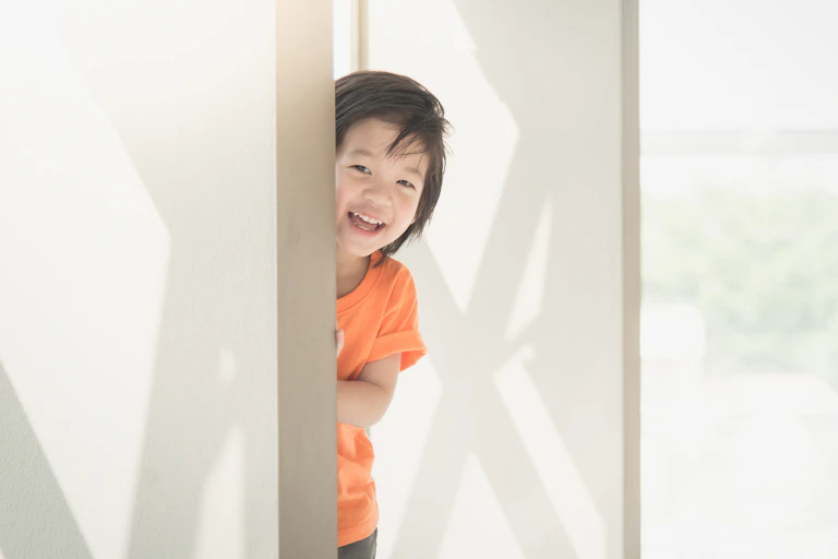 Little boy peering out from hiding place