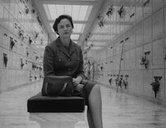 Black and white photo of a woman in a suit sitting in a mausoleum