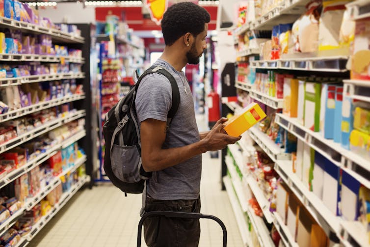 مرد ایستاده در سوپرمارکت در حال انتخاب غذا