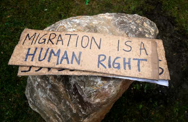 A placard on a rock that reads Migration is a human right.