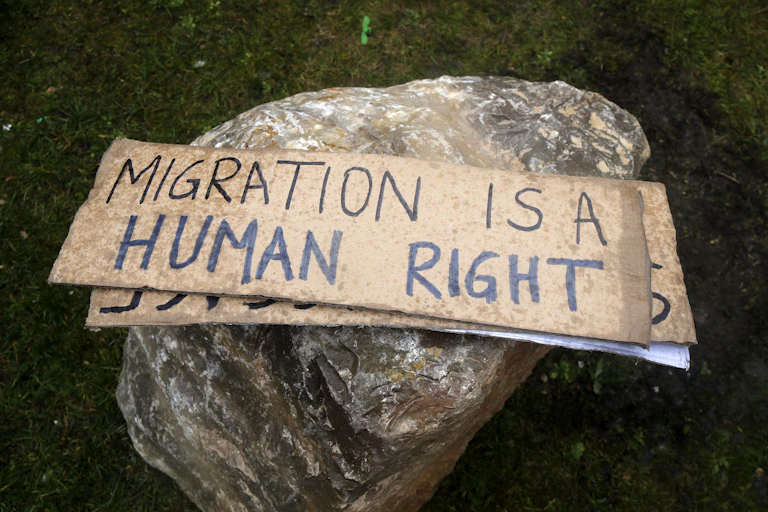 A placard on a rock that reads Migration is a human right.