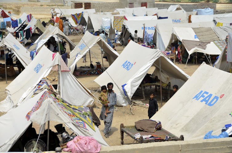 People walk past a series of white tents.