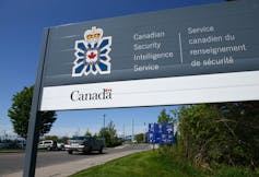 A sign for the Canadian Security Intelligence Service with trees behind it.