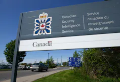 A sign for the Canadian Security Intelligence Service with trees behind it.