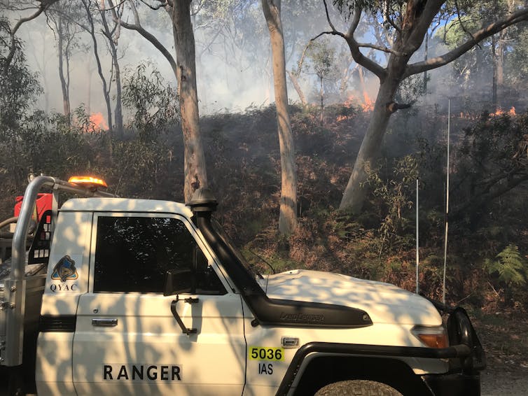 QYAC Ranger vehicle in the foreground while a cultural burn is underway on the hillside in the background