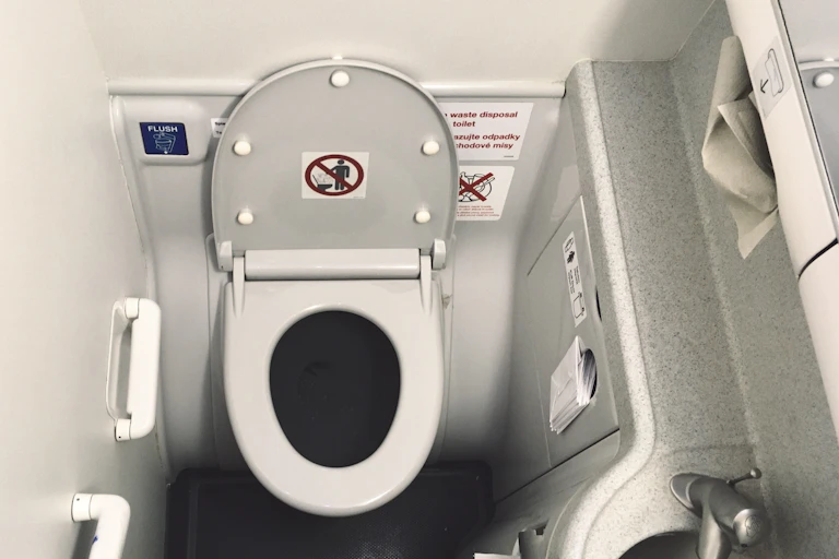 Airplane toilet with the lid up and small sink next to it
