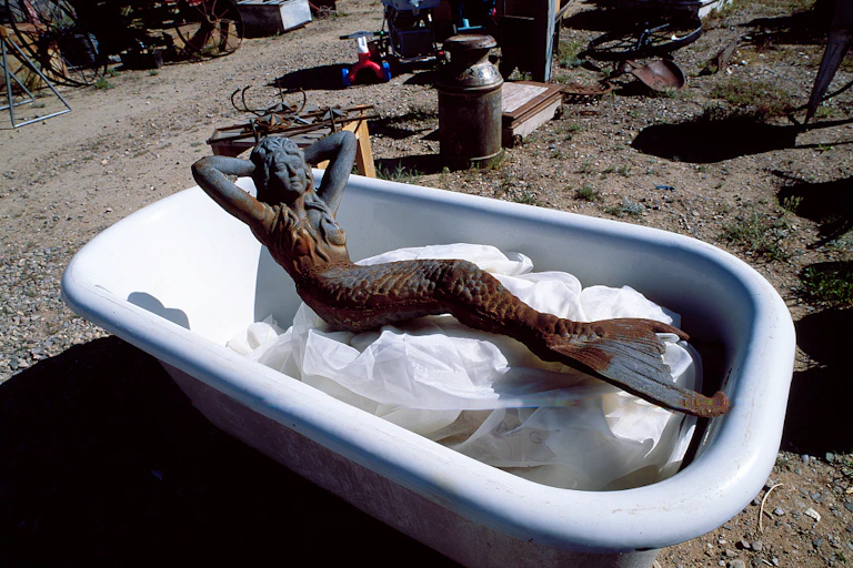 Escultura de metal de una sirena dentro de una bañera.