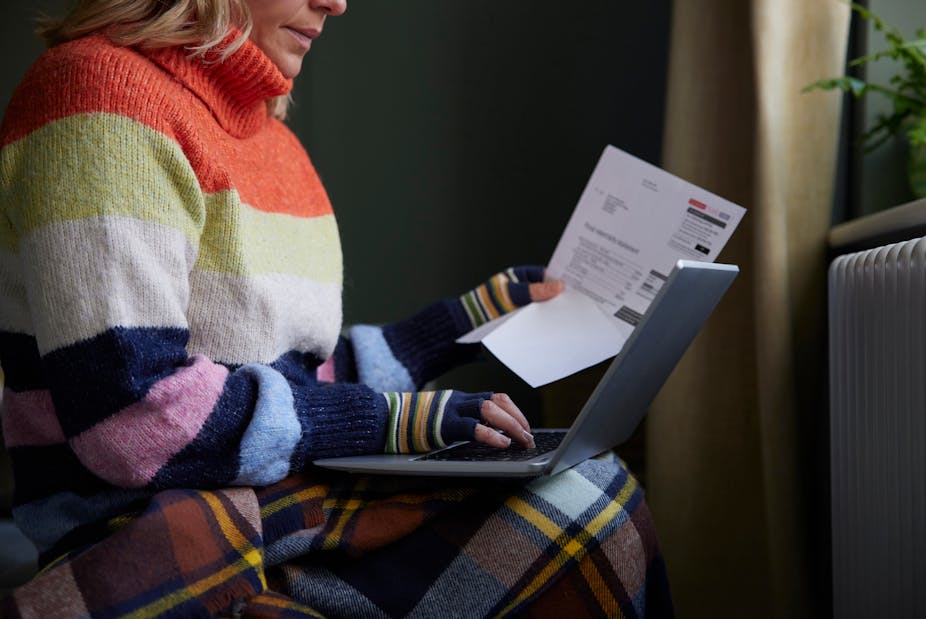 A woman sitting in front of a radiator with a laptop on her lap.