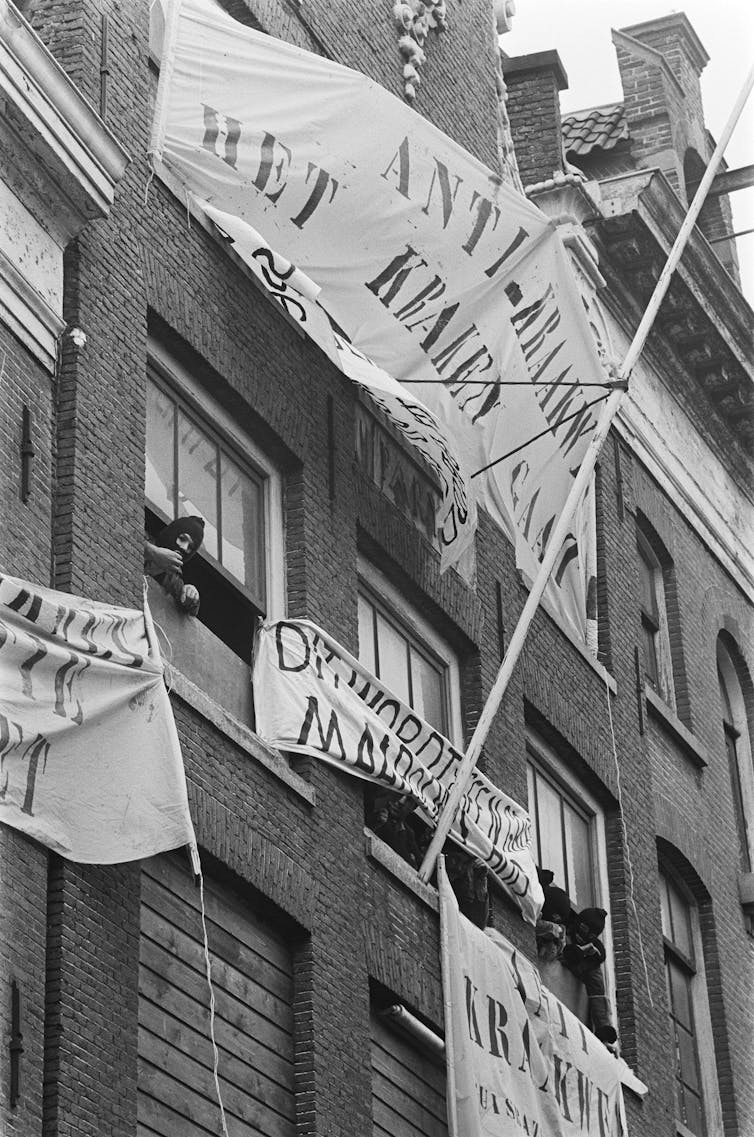 Flags with slogans outside a brick building.