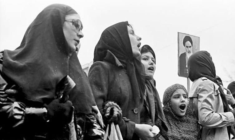 Iran 1979. Women protesters wearing hijabs and holding up a placard of the Ayatollah Khomeini.